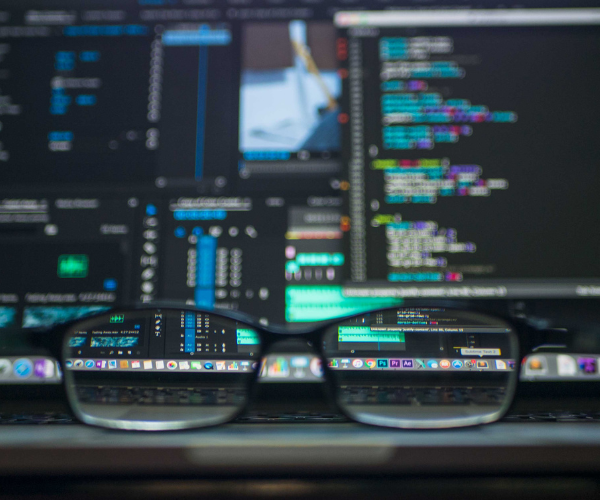 A pair of glasses in front of a computer screen with a lot of data displayed
