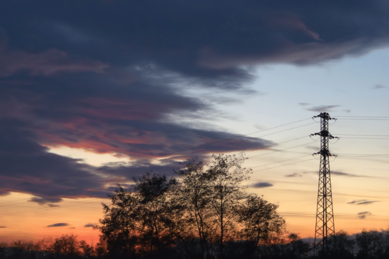 Electricity pylons and power lines against a sunset